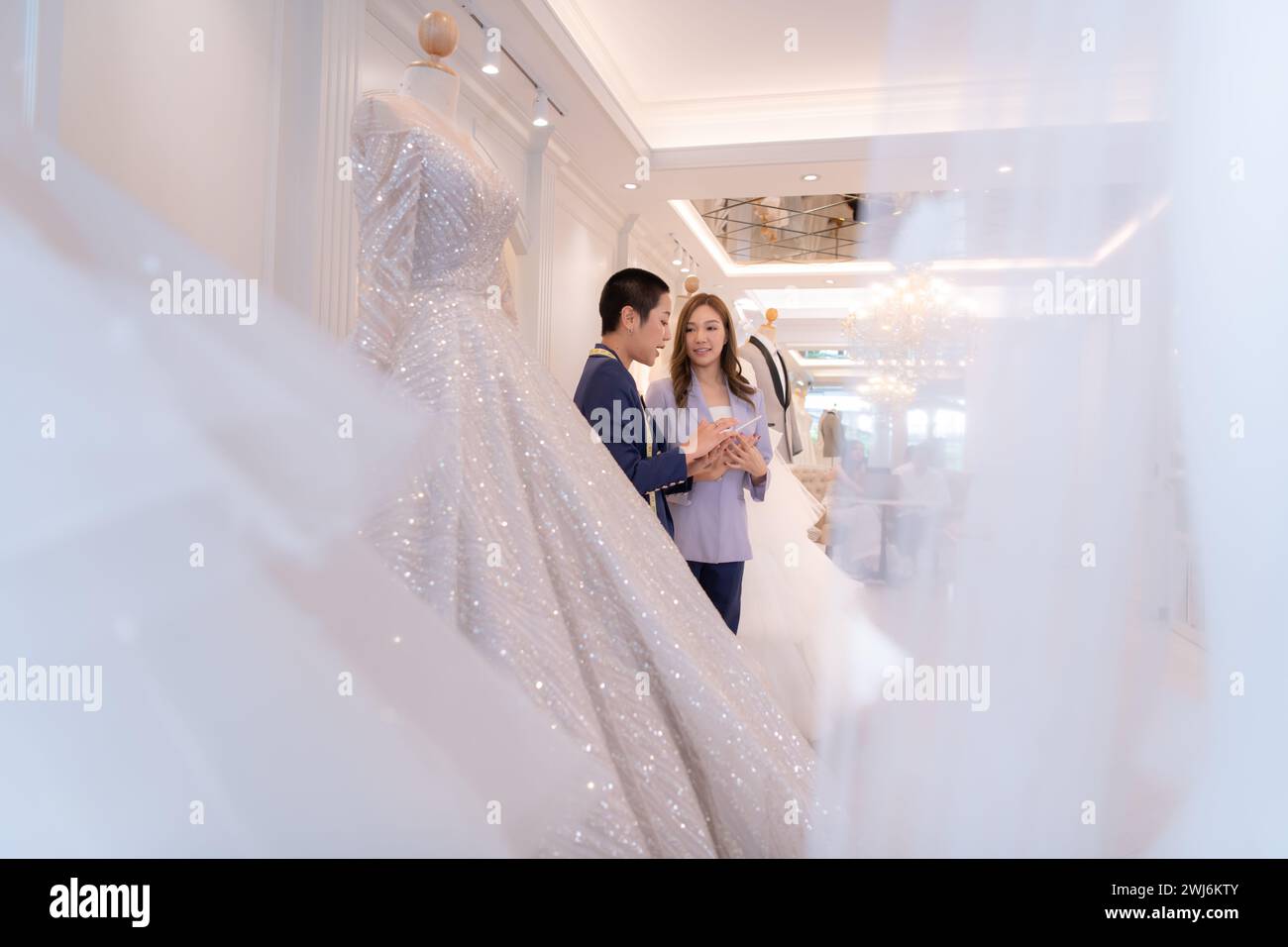 Beide asiatischen Modedesigner arbeiten im Hochzeitskleiderladen mit Hochzeitskleidern Stockfoto