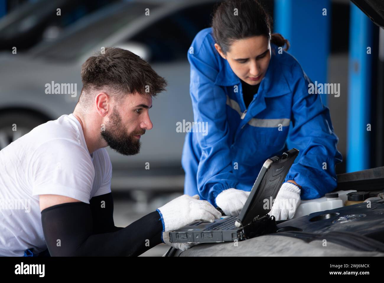 Professioneller Automechaniker, Mann und Frau, die zusammen in einer Autowerkstatt arbeiten. Stockfoto