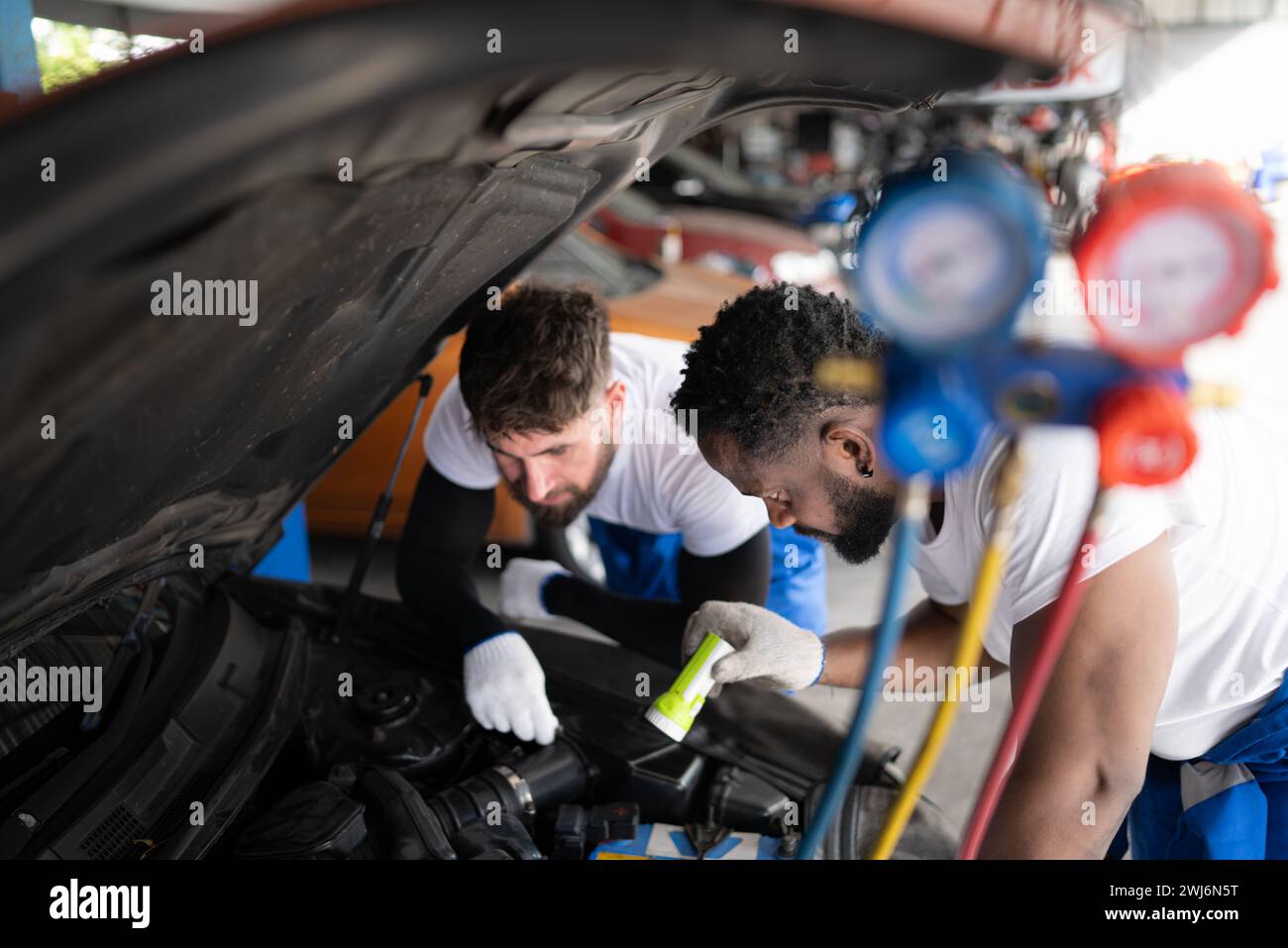Automechaniker, der in einer Autowerkstatt arbeitet und die Funktion der Klimaanlage und des Kältemittels des Fahrzeugs überprüft. Stockfoto