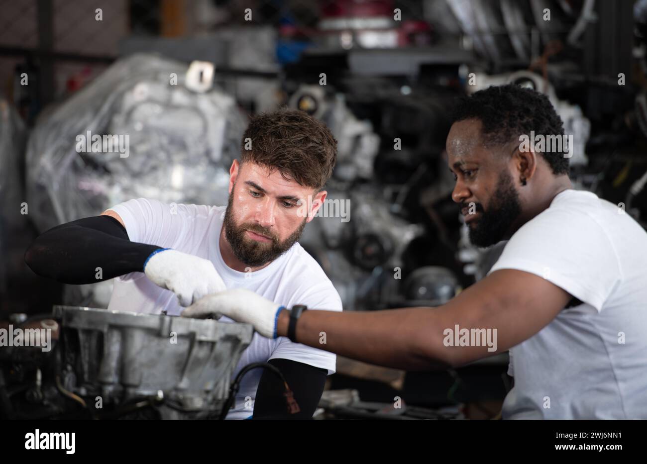 Zwei Männer reparieren den Motor in der Autowerkstatt, selektiver Fokus. Stockfoto