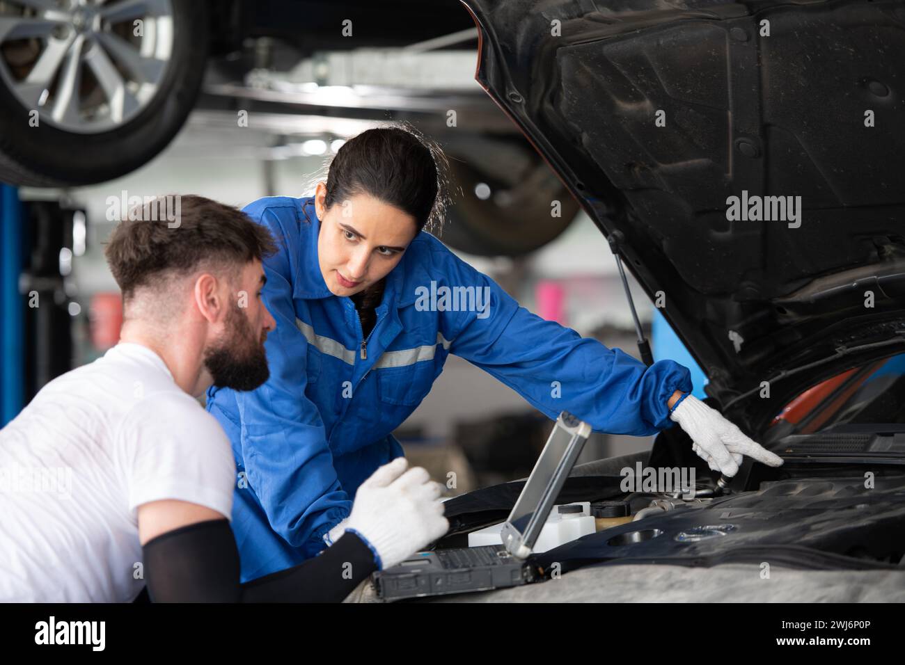 Professioneller Automechaniker, Mann und Frau, die zusammen in einer Autowerkstatt arbeiten. Stockfoto