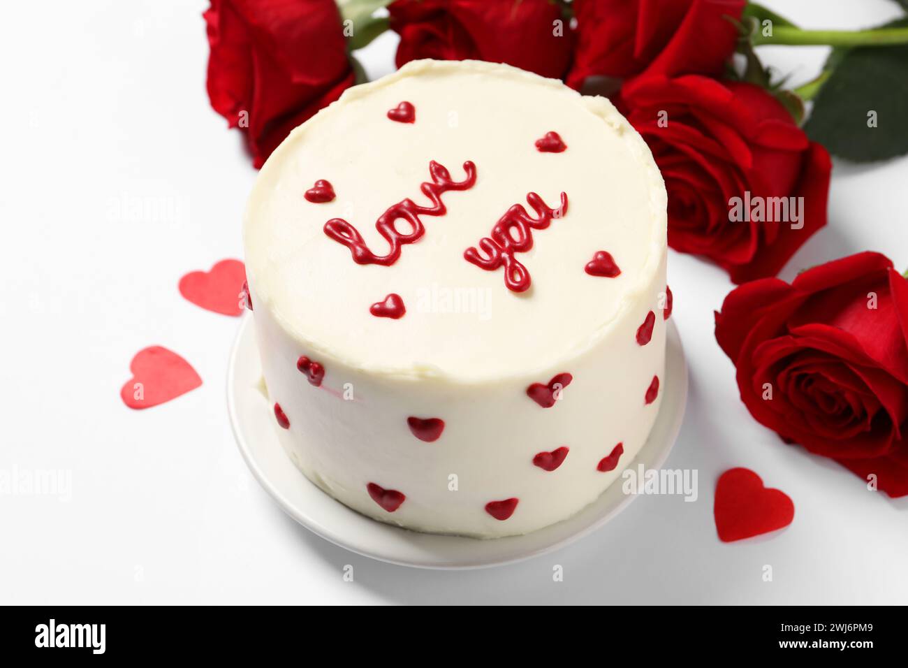 Bento Kuchen mit Text Love You, Papierherzen und Rosen auf weißem Tisch. St. Valentinstag-Überraschung Stockfoto