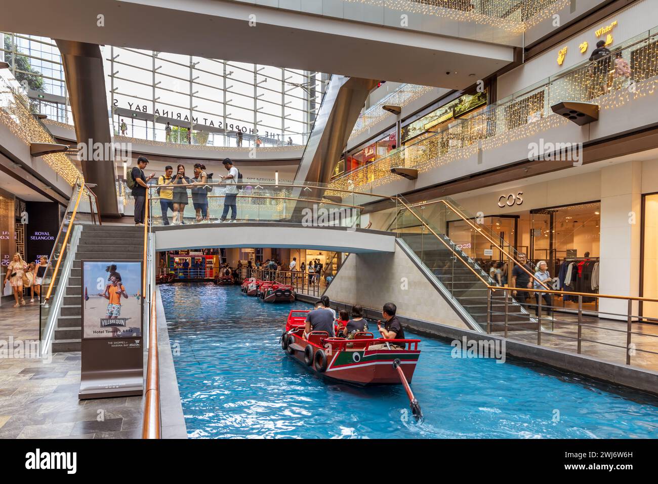 Besucher genießen SAMPANFAHRTEN entlang des Canal in den Shoppes at Marina Bay Sands. Stockfoto