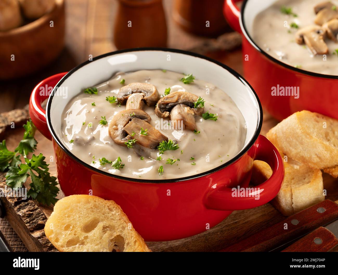 Zwei Schüsseln cremige Pilzsuppe mit Pilzscheiben und Petersilie auf einem rustikalen Holztablett Stockfoto