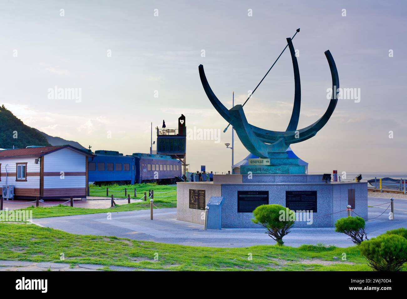 Gangneung City, Südkorea - 29. Juli 2019: Jeongdongjin Hourglass Park zeigt eine Sonnenuhr-Skulptur im Vordergrund mit Zügen auf den Gleisen BE Stockfoto