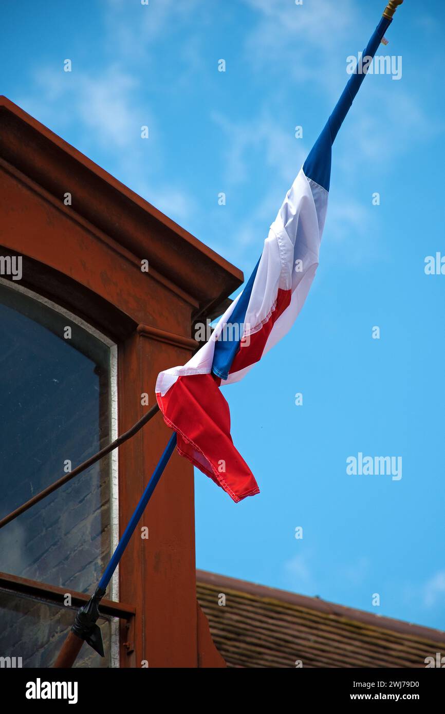 Französische Flagge, die um den Fahnenmast gegen den blauen Himmel gedreht wurde Stockfoto