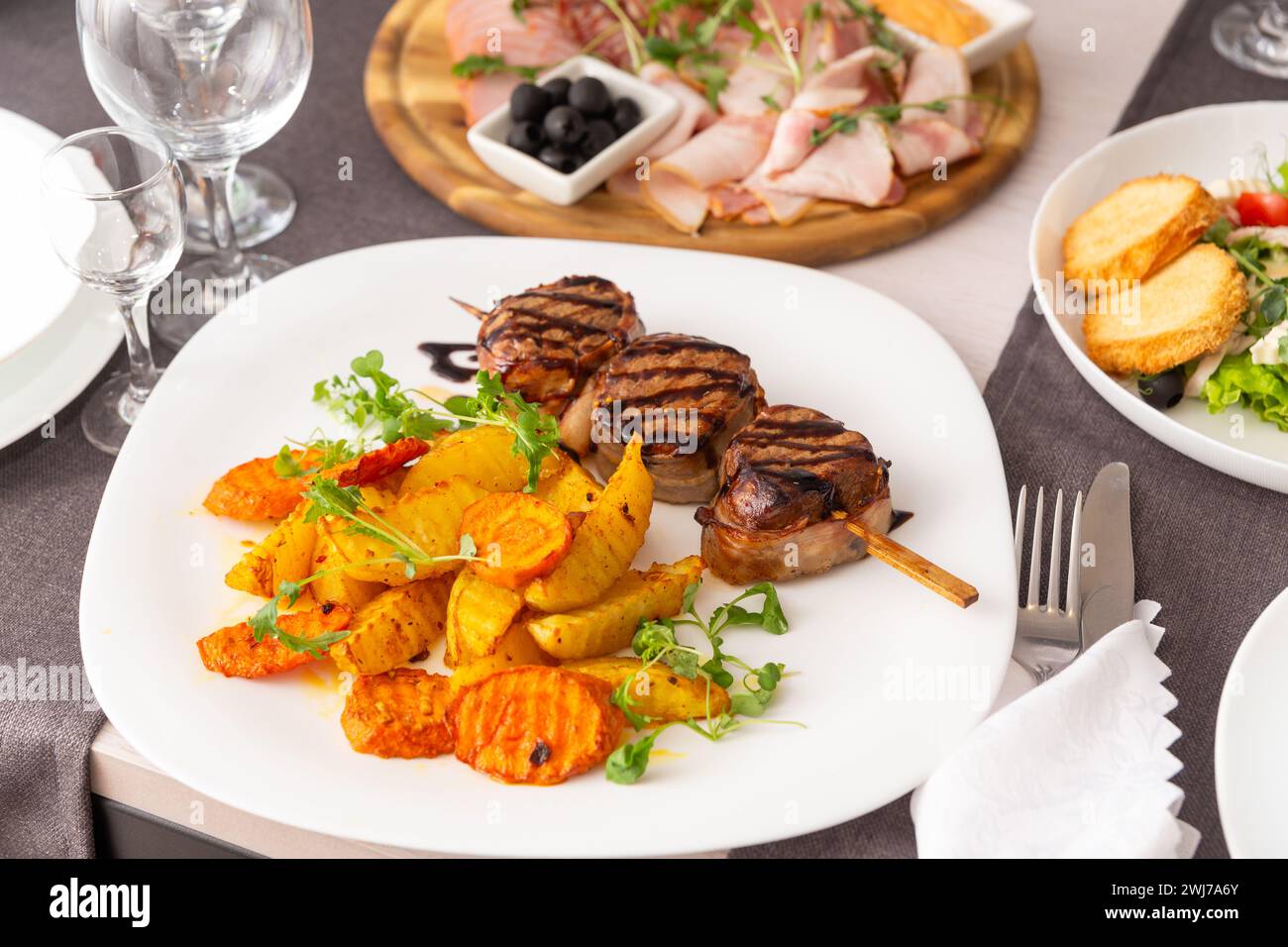 Gegrilltes Fleisch auf einem Spieß mit einer Beilage aus Gemüse und Pommes Frites auf einem weißen Teller. Serviert Gerichte für eine Person in einem Café oder Restaurant. Stockfoto