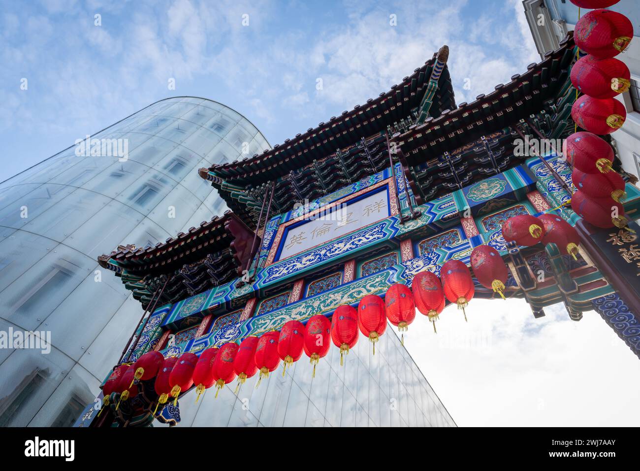 London. UK- 02.11.2024. Ein Blick von oben auf das reich verzierte und farbenfrohe Eingangstor im Stil der Ching Dynastie in China Town mit dem modernen Swiss Centre in t Stockfoto