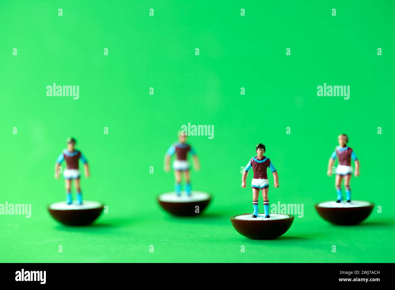 Eine Gruppe von Subbuteo Miniaturfiguren, die in den Farben der Aston Villa FC Heimmannschaft gemalt sind: Dunkelrote und blaue Hemden, weiße Shorts und dunkelrote und blaue Socken Stockfoto