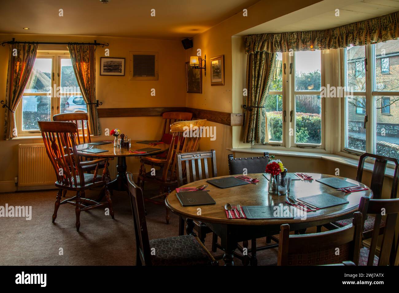 Das Innere eines Wirtshauses, das warm und einladend ist, mit Tischen, die für die Gäste bereit sind, die kulinarischen Köstlichkeiten der Pubs zu probieren. Stockfoto