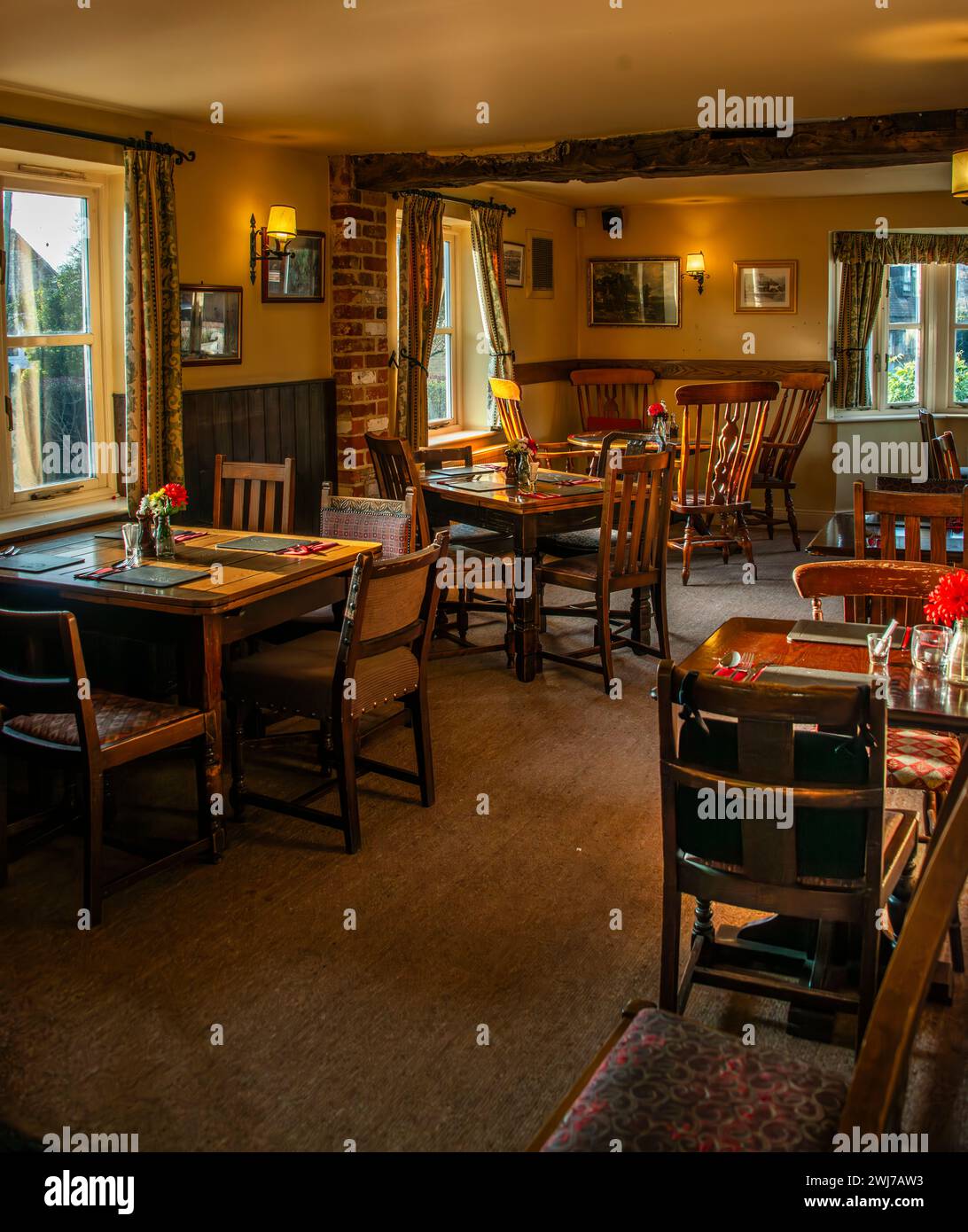 Das Innere eines Wirtshauses, das warm und einladend ist, mit Tischen, die für die Gäste bereit sind, die kulinarischen Köstlichkeiten der Pubs zu probieren. Stockfoto
