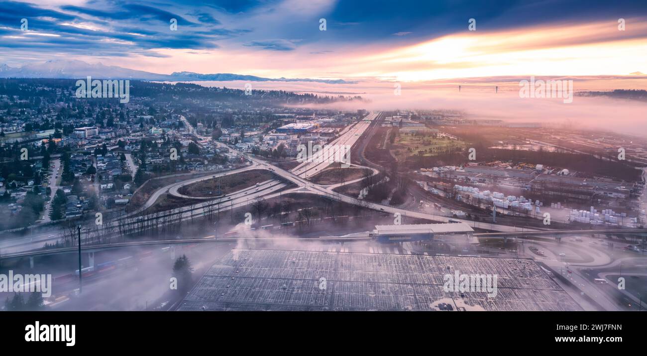 Blick aus der Vogelperspektive auf die Stadt bei Sonnenuntergang, mit Autobahnbrücken im Nebel Stockfoto