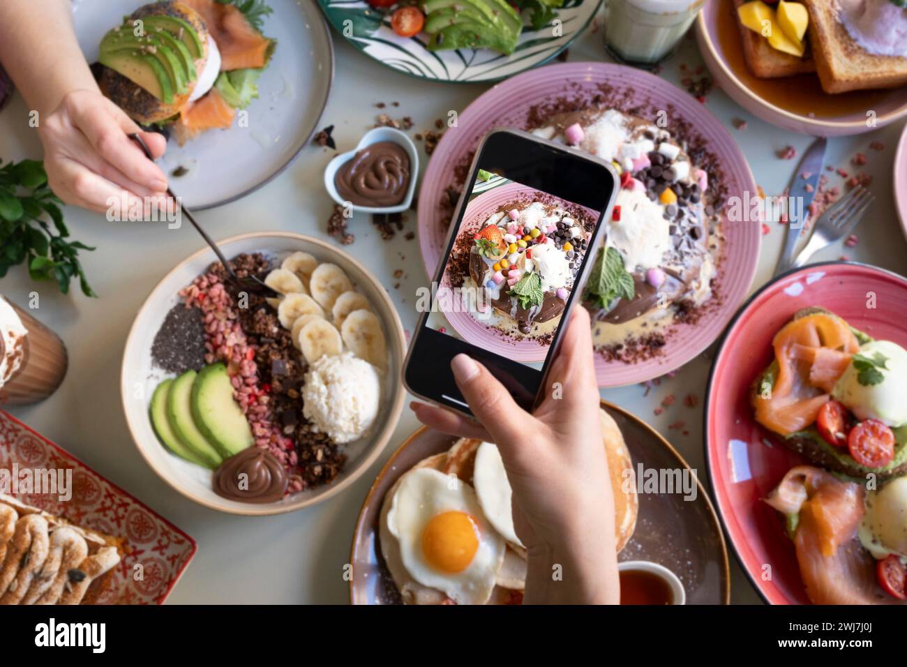 Freunde, die während des Brunch im Restaurant Fotos von Speisen auf dem Tisch machen Stockfoto