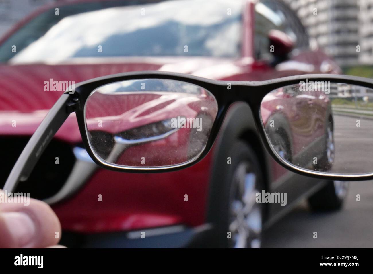 Schmutzige Brillengläser, die ein unscharfes Foto des Autos zeigen Stockfoto