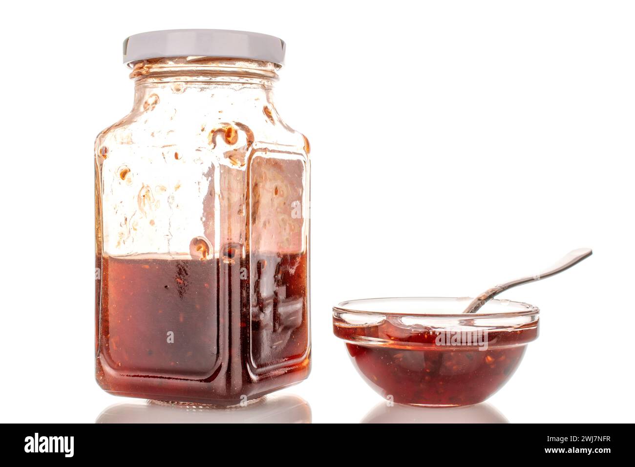 Erdbeermarmelade in einem Glas und in einer Glasuntertasse, Makro, isoliert auf weißem Hintergrund. Stockfoto