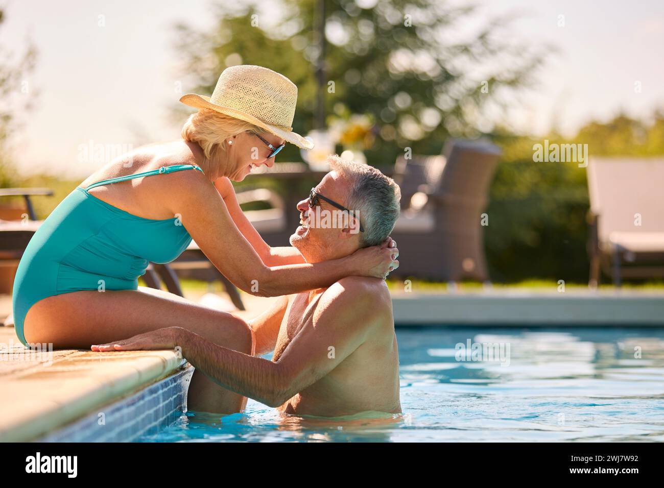 Liebevolles Seniorenpaar Im Urlaub In Badekleidung, Entspannend Am Hotel Swimmingpool Stockfoto