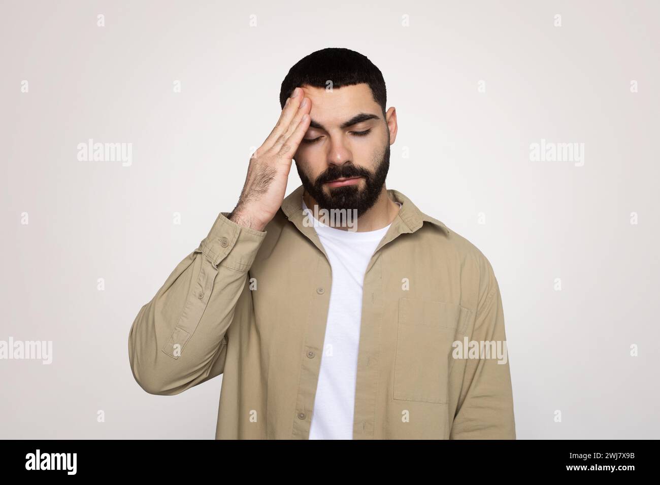 Trauriger junger lateinmann mit Bart in lässiger Hand auf die Stirn gelegt, leidet an Kopfschmerzen Stockfoto