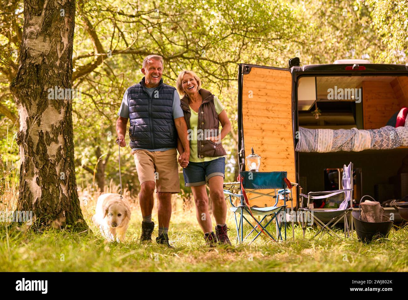 Seniorenpaar Camping auf dem Land mit Wohnmobil, der Labrador Dog für Einen Spaziergang mitnimmt Stockfoto