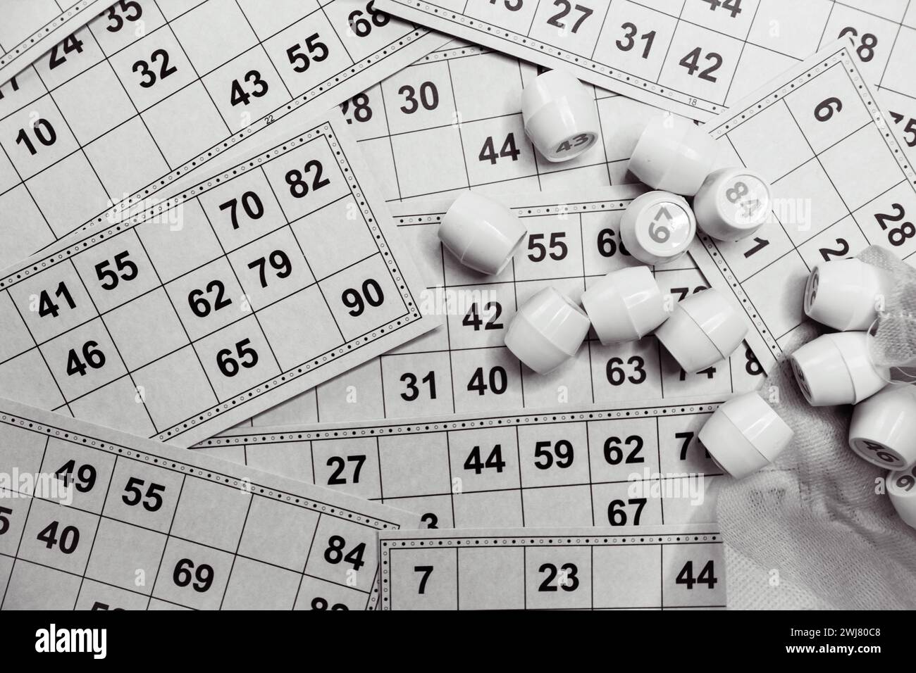 Lottospiel spielen, Schwarzweiß. Würfel mit Figur auf Bingo-Kartenhintergrund, schwarz-weiß. Nostalgie Lifestyle. Tischspiele. Retro-Spiele. Stockfoto