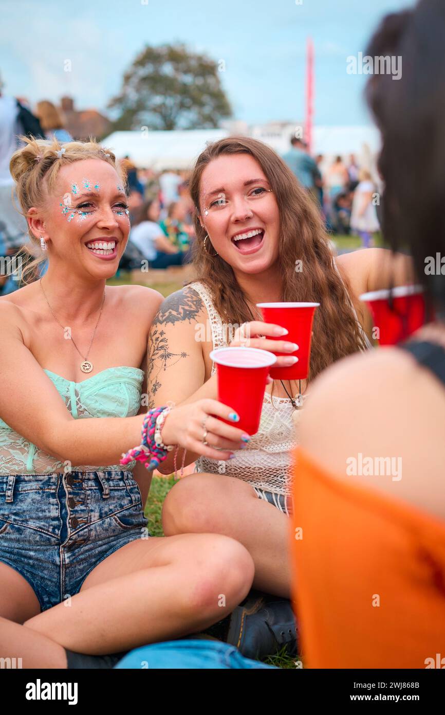 Drei Weibliche Freundinnen Tragen Glitter Und Haben Spaß Beim Summer Music Festival, Das Cheers With Drinks Macht Stockfoto