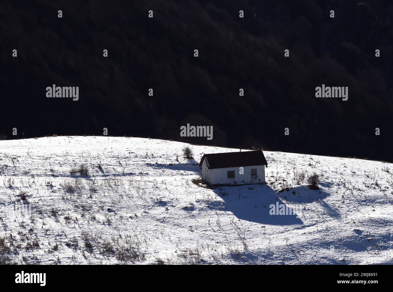 Ruhe im Schnee. Ein einsames Haus auf dem Berg. Hintergrundbeleuchtung leuchtet. Ponikva Mazedonien 2024. Stockfoto