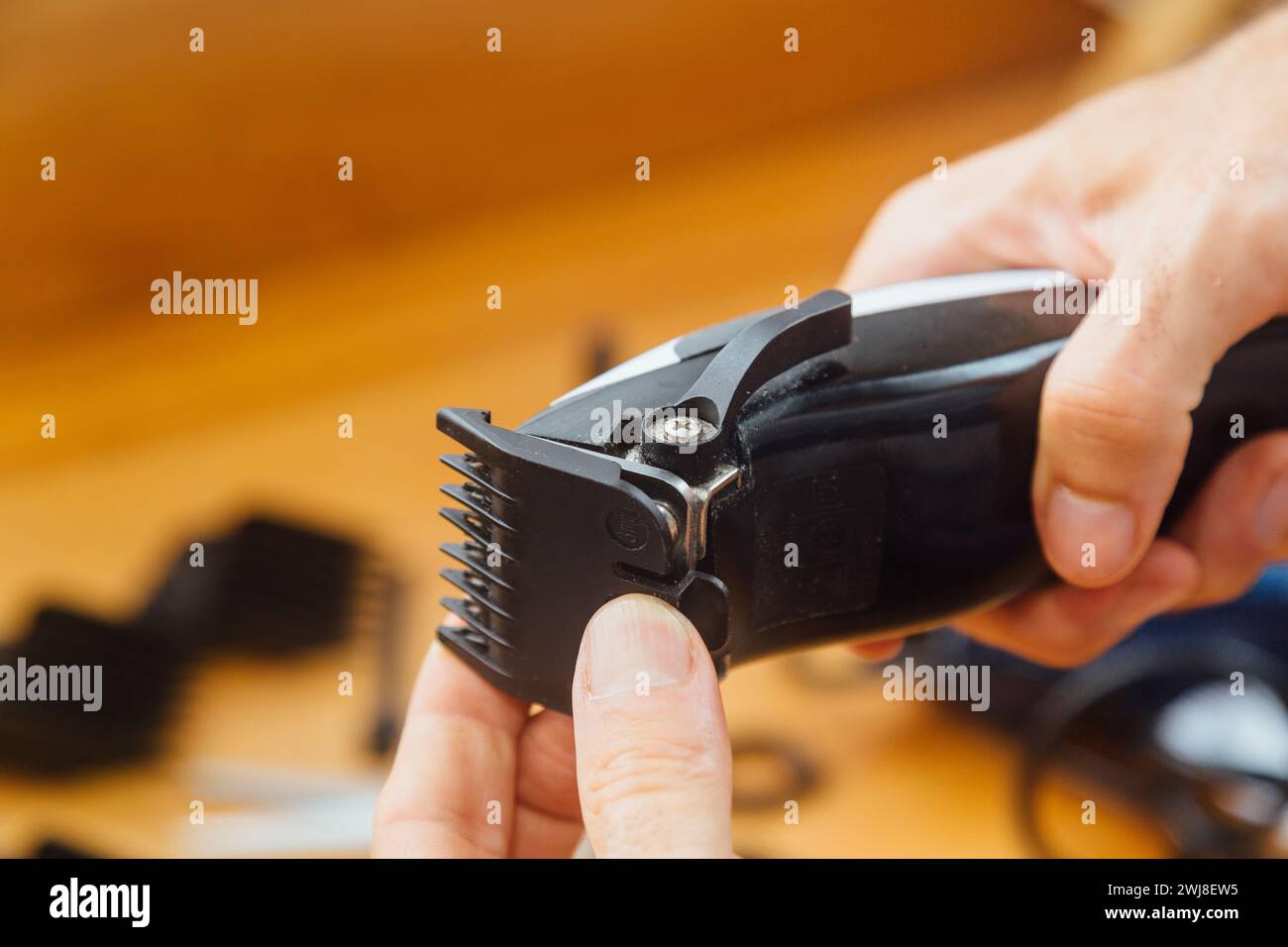 Der Friseur wechselt den Kamm seiner Haarschneidemaschine. Austausch der Düse eines elektrischen Haarschneiders. Hände wechseln Düsen elektrische Haarschneide Stockfoto