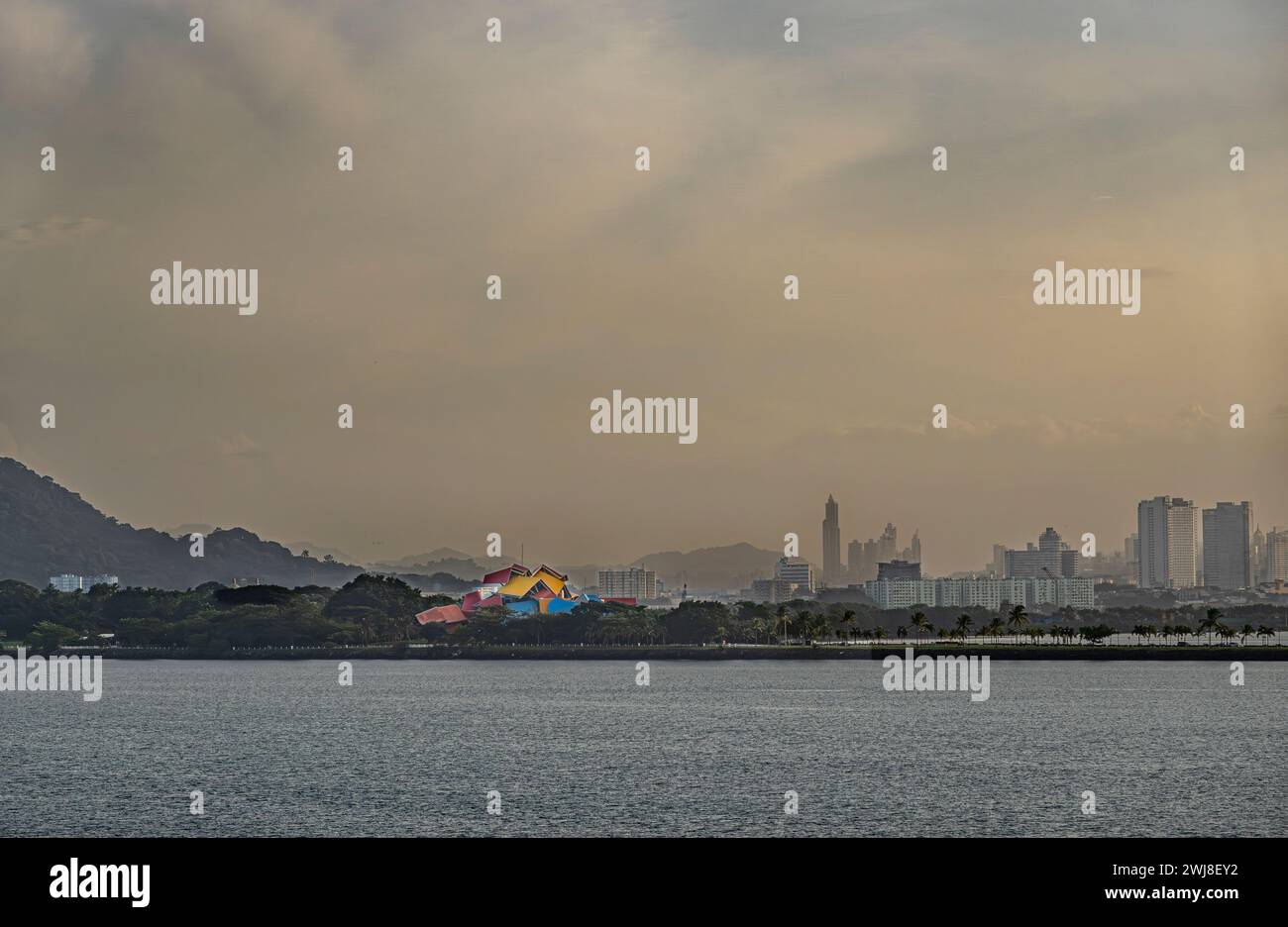Panamakanal, Panama - 24. Juli 2023: Das farbenfrohe Biodiversitätsmuseum hebt sich am Eingang in der nebligen Morgenwolkenlandschaft hervor. Stadtlandschaft, grüner Berg Stockfoto