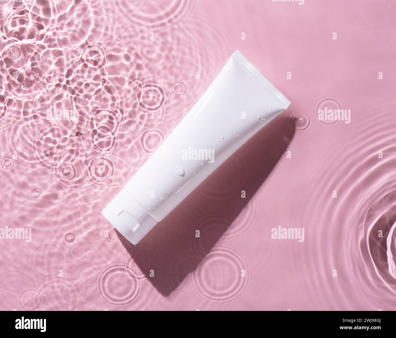 Mockup von Make-up-Creme oder Lotionflasche auf rosa Wasserhintergrund. Stockfoto