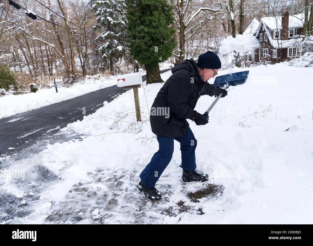 Chappaqua, New York - 13. Februar 2024 - Ein Mann schaufelt seine Auffahrt, nachdem ein Wintersturm über einen Fuß schweren nassen Schnee auf dem Westchester County New Yo abgefeuert hatte Stockfoto