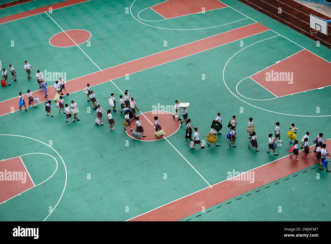 Schulkinder laufen auf dem Basketballfeld der Schule. Shenzhen, China. Stockfoto