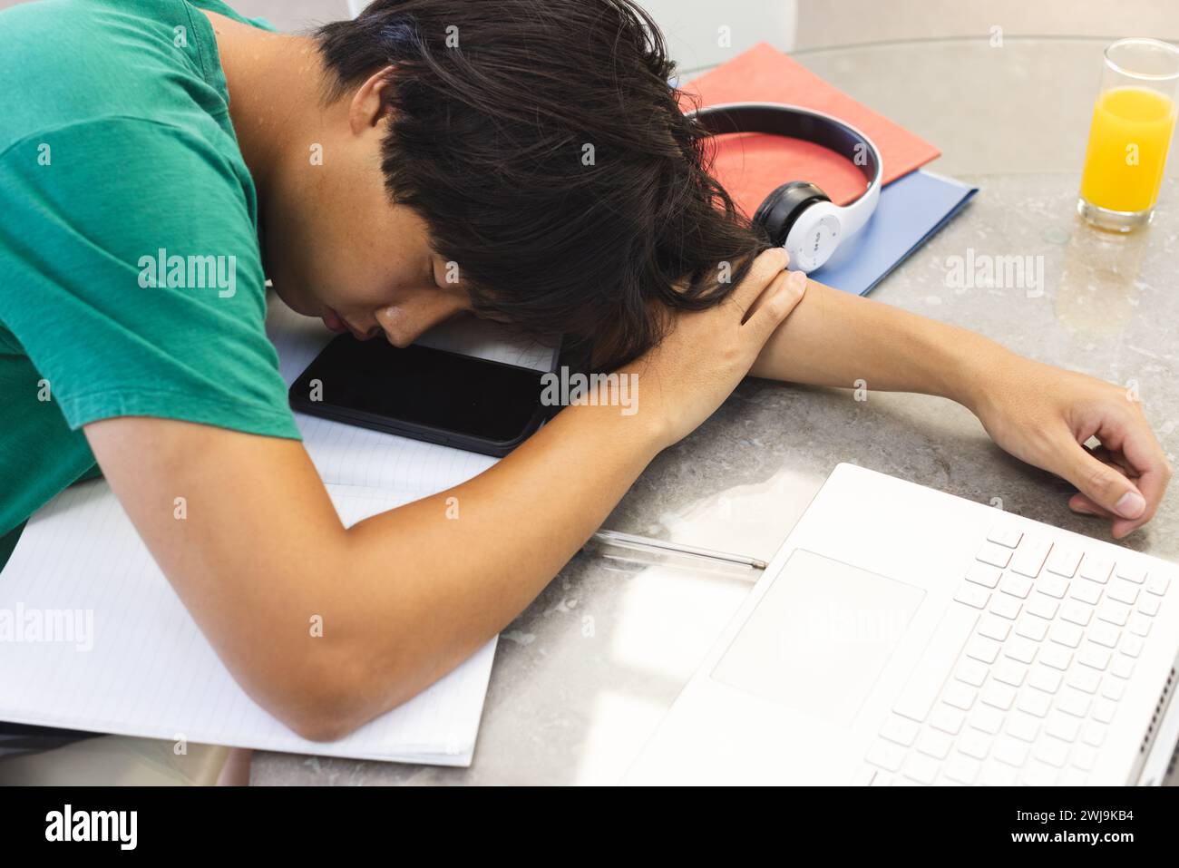Erschöpfter asiatischer Teenager schläft zu Hause auf seinem Schreibtisch, mit Kopierraum Stockfoto