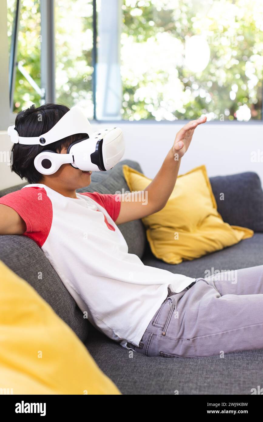 Der Teenager Asian Boy erkundet die virtuelle Realität von einer Couch zu Hause aus Stockfoto