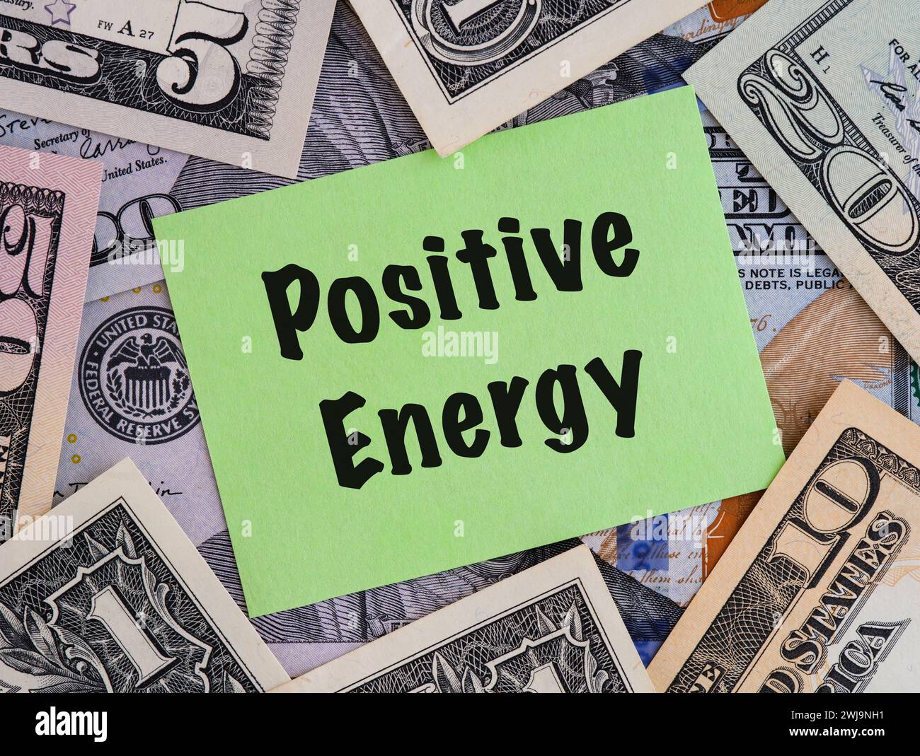 Eine Grünbuch-Notiz mit dem Satz positive Energie auf dem Hintergrund von US-Dollar-Scheinen. Stockfoto
