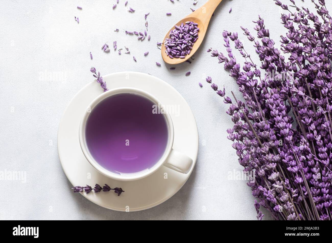 Tasse Lavendeltee mit getrockneten Lavendelblüten auf rustikalem Tisch, Kräuter-entspannender Tee. Lavendula oleum Stockfoto