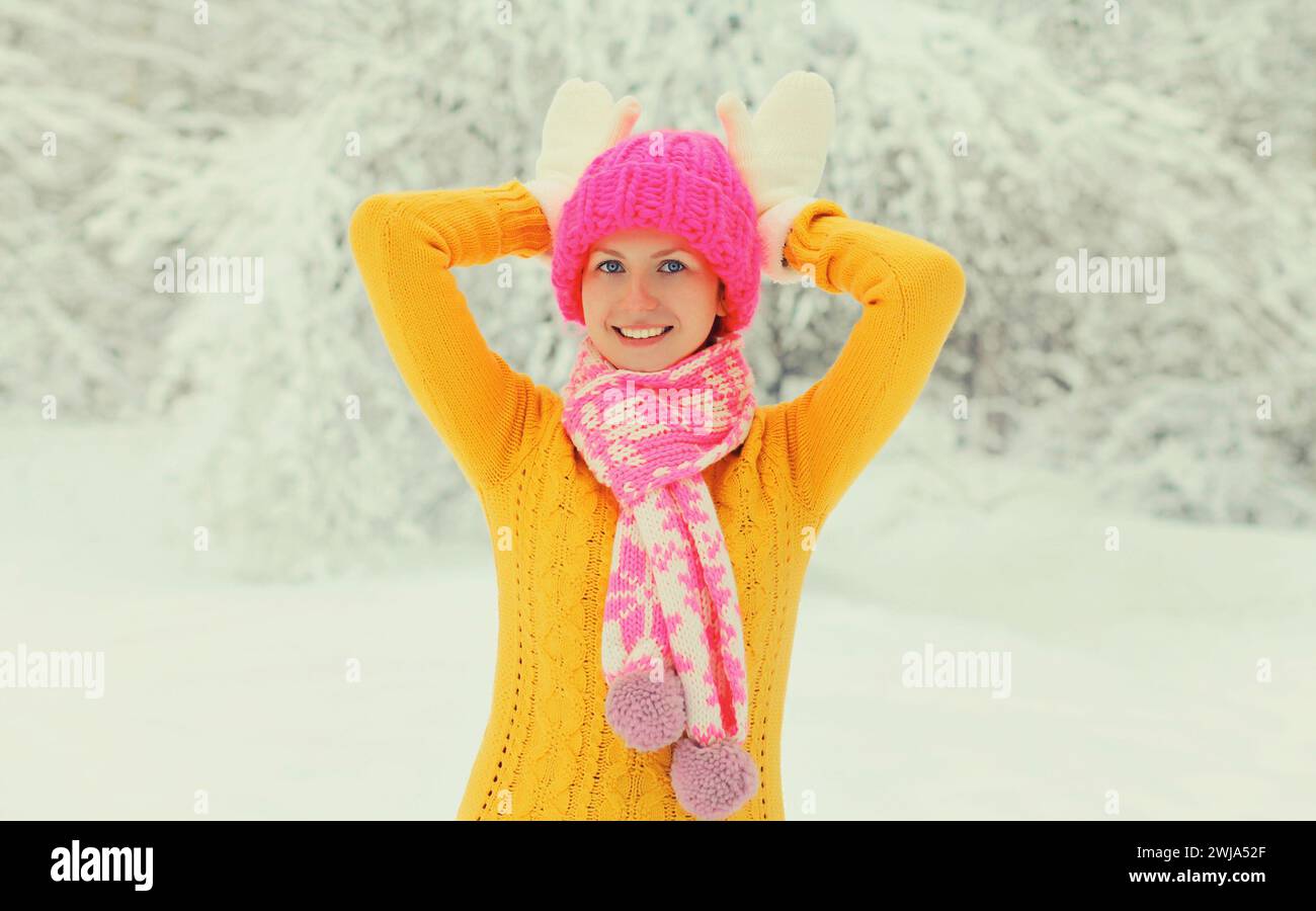 Winterporträt einer fröhlichen, fröhlichen jungen Frau, die Spaß in bunten Strickmützen hat, Schal genießt das Wetter im schneebedeckten Park Stockfoto