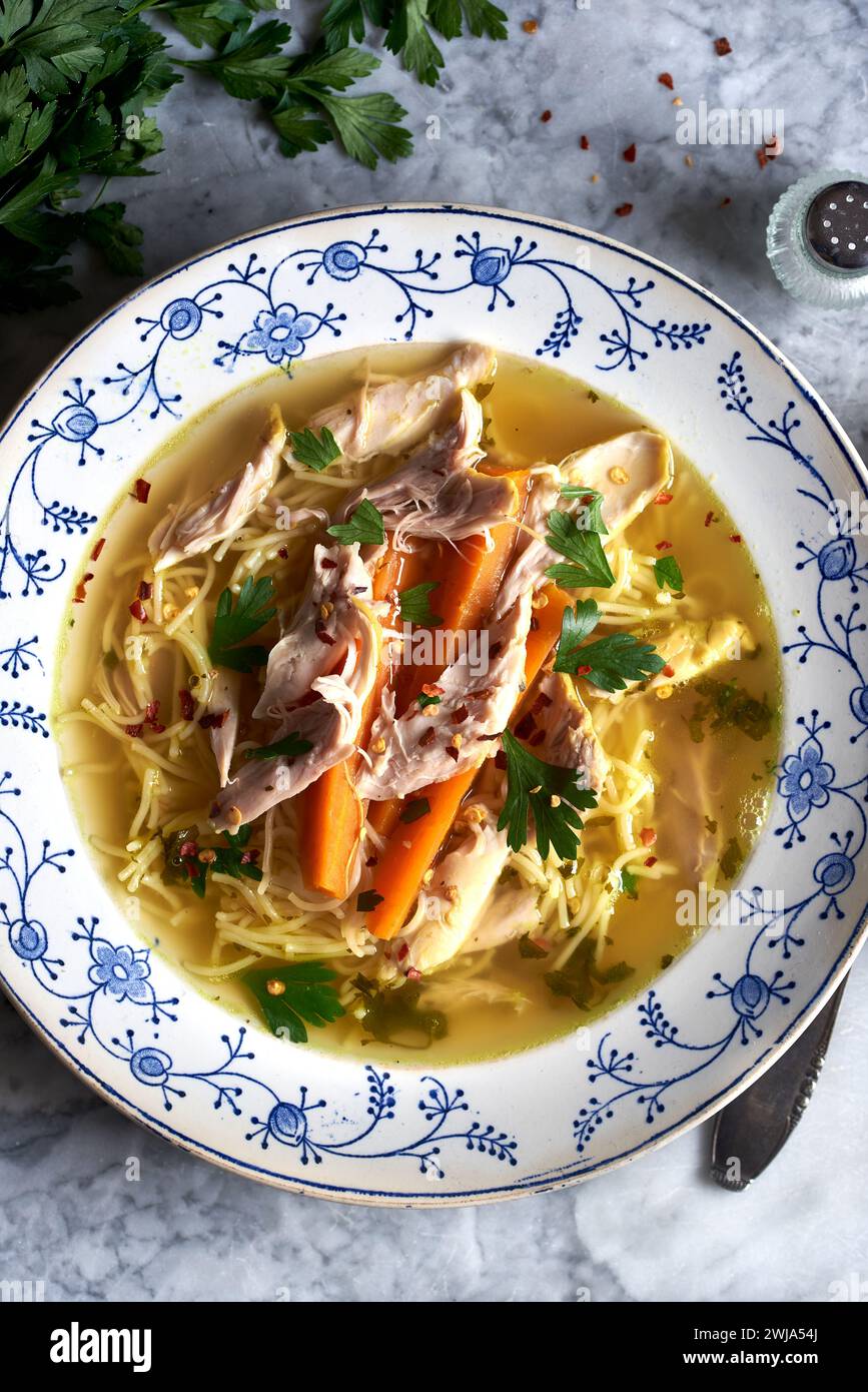 Warme Schüssel mit Hühnernudelsuppe mit Karotten und Petersilie, perfekt für Komfortgerichte Stockfoto
