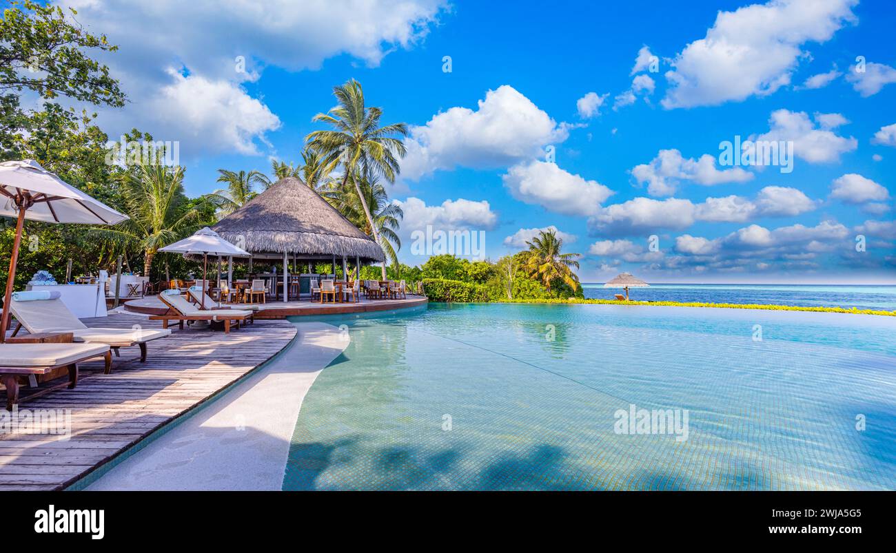 Atemberaubende Landschaft, Swimmingpool, sonniger blauer Himmel. Tropisches Resort-Hotel auf den Malediven. Freizeit Entspannen Wohlbefinden friedliche Atmosphäre, Liegen, Sonnenschirme Stockfoto