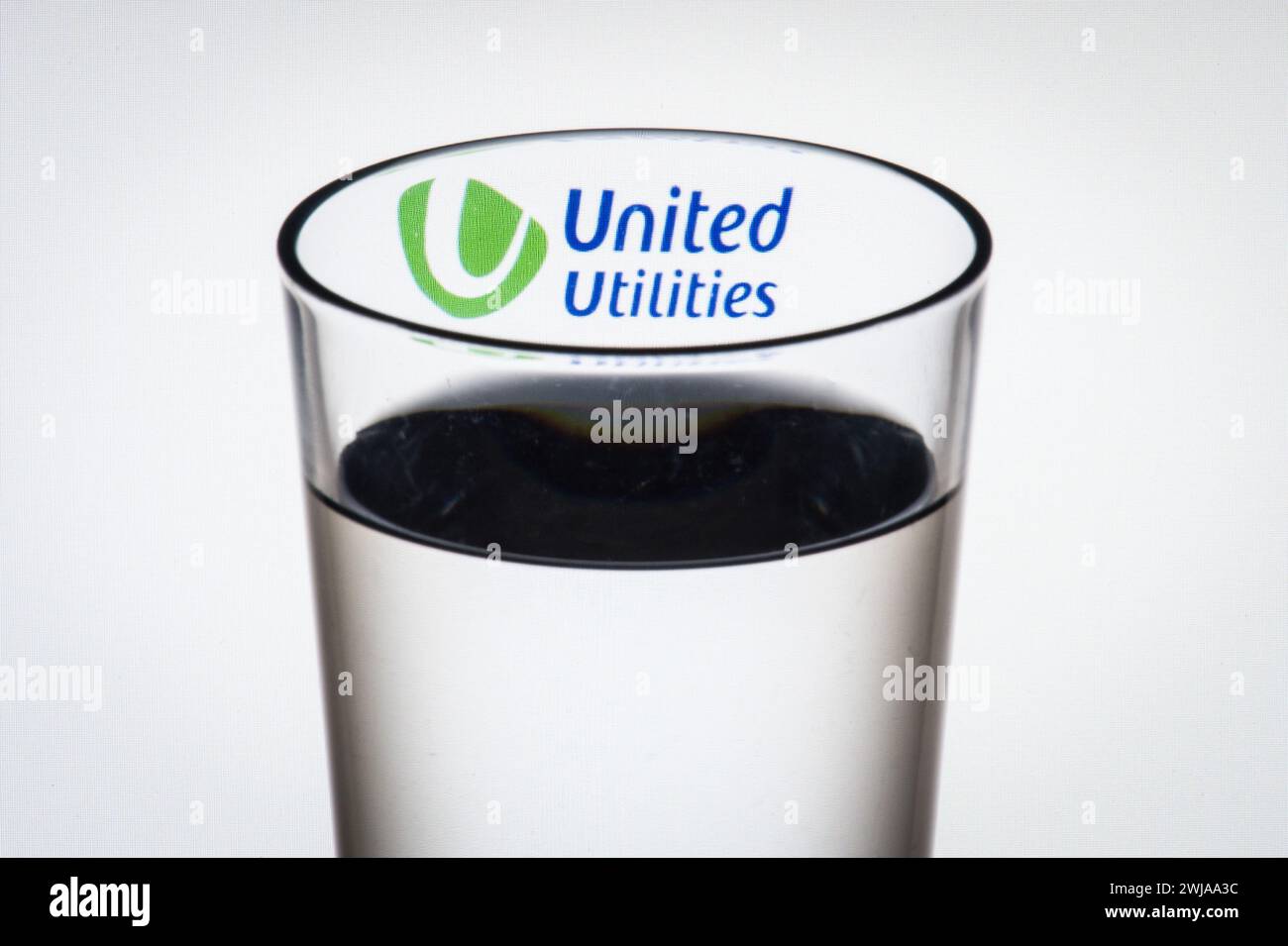 Aktenfoto vom 8/2016 mit dem Logo der Wassergesellschaft United Utilities durch ein Glas Wasser. Der North West Water Provider United Utilities sagte, dass seine Leistung durch eine Reihe von Stürmen im vergangenen Jahr vom Kurs abgefallen sei, sagte aber, dass seine finanziellen Aussichten unverändert bleiben. Das Unternehmen sagte, dass der außergewöhnlich hohe Niederschlag einen Anteil von 25 Millionen Pfund an den Anreizzahlungen, die es für das Geschäftsjahr erhalten wird, einbüßen würde. Ausgabedatum: Mittwoch, 14. Februar 2024. Stockfoto