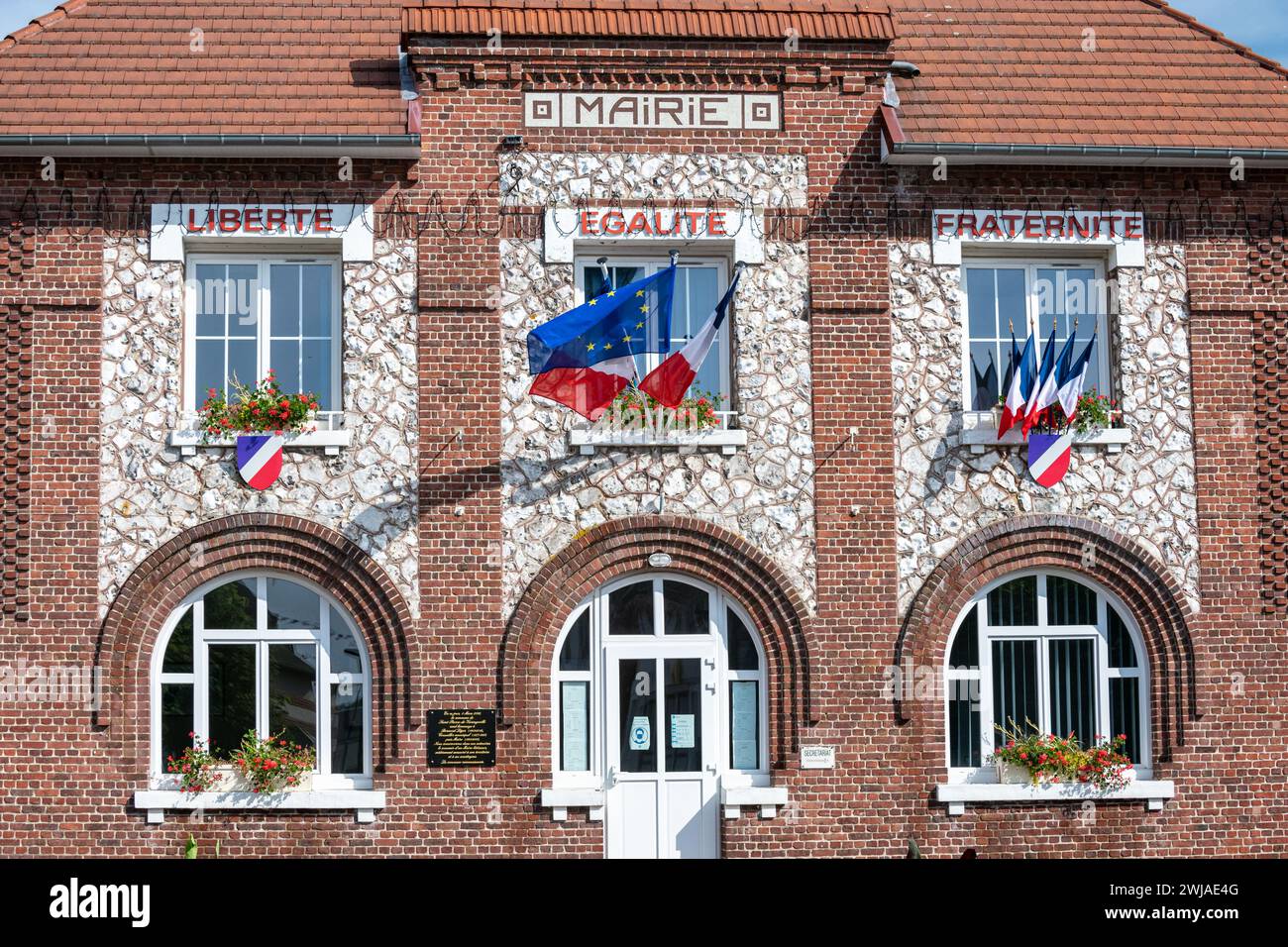 Fassade eines Rathauses mit französischer blauer, weißer und roter Flagge und europäischer Flagge anlässlich des Nationalfeiertags am 14. Juli und Motto auf dem Stockfoto