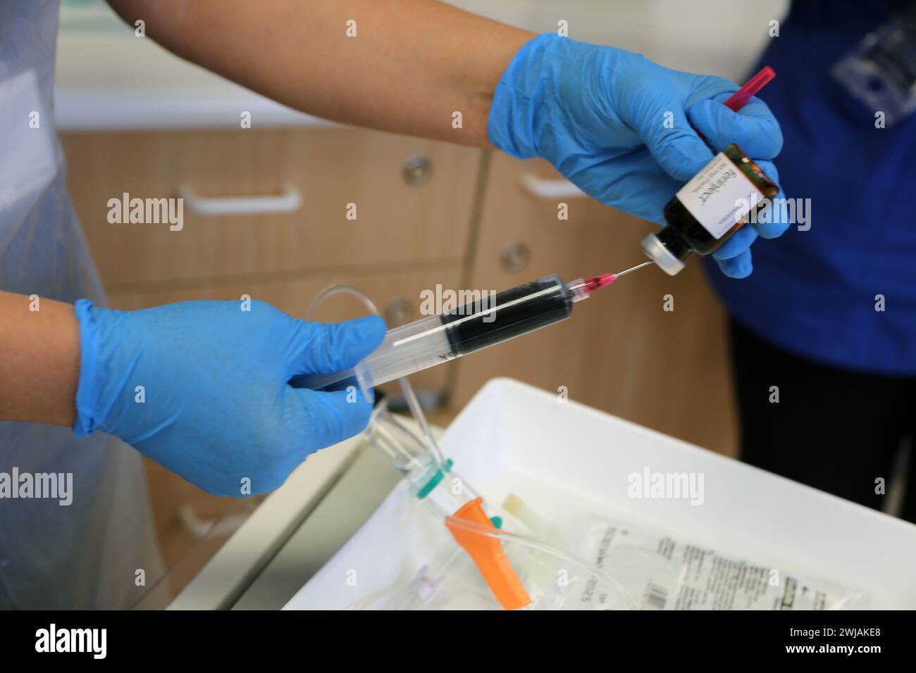 Krankenschwester bereitet Ferinject-Lösung vor, die für die intravenöse Verabreichung einer Eiseninfusion an einen Patienten im Hospital Surrey England vorbereitet wird Stockfoto