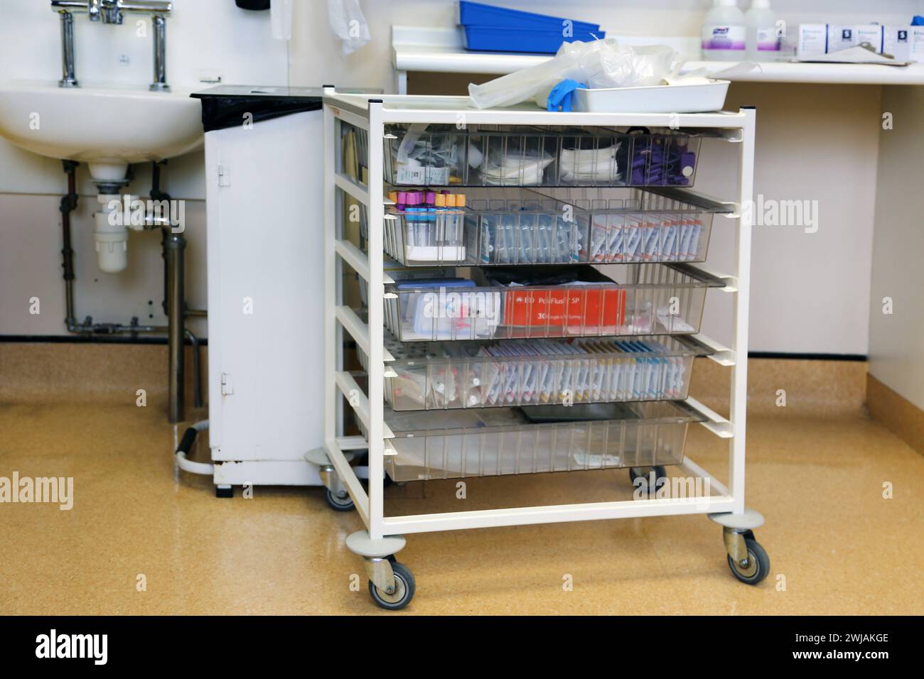 Medizinischer Trolley mit Röhrchen, Medikamenten, Gesichtsmasken und Schürze im Krankenhaus Surrey England Stockfoto