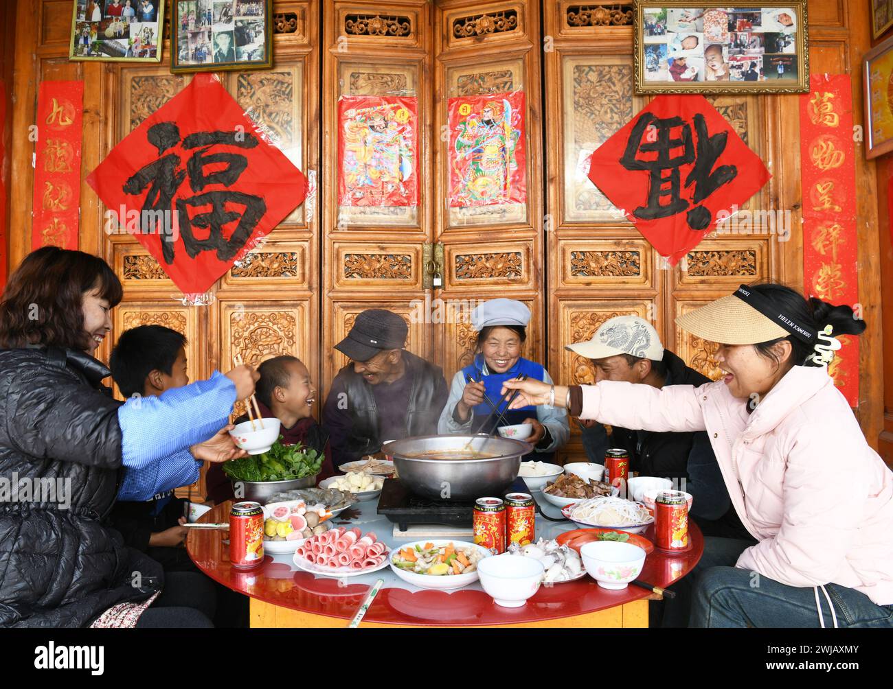 Peking, chinesische Provinz Yunnan. Februar 2024. Eine einheimische Familie genießt ihr Abendessen im Dorf Wenping im Bezirk Jianchuan in der Autonomen Präfektur Dali Bai, südwestchinesische Provinz Yunnan, 13. Februar 2024. Die Menschen im ganzen Land tauchten in die festliche Atmosphäre des chinesischen Neujahrs ein, indem sie traditionelle Speisen und lokale Snacks genossen. Quelle: Zhao Qingzu/Xinhua/Alamy Live News Stockfoto