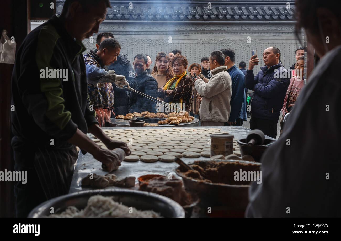 Peking, Chinas Provinz Jiangsu. Februar 2024. Touristen warten darauf, Sesamkuchen in einem Geschäft im Kreis Rudong in Nantong, ostchinesischer Provinz Jiangsu, am 13. Februar 2024 zu kaufen. Die Menschen im ganzen Land tauchten in die festliche Atmosphäre des chinesischen Neujahrs ein, indem sie traditionelle Speisen und lokale Snacks genossen. Quelle: Jiang Yi/Xinhua/Alamy Live News Stockfoto