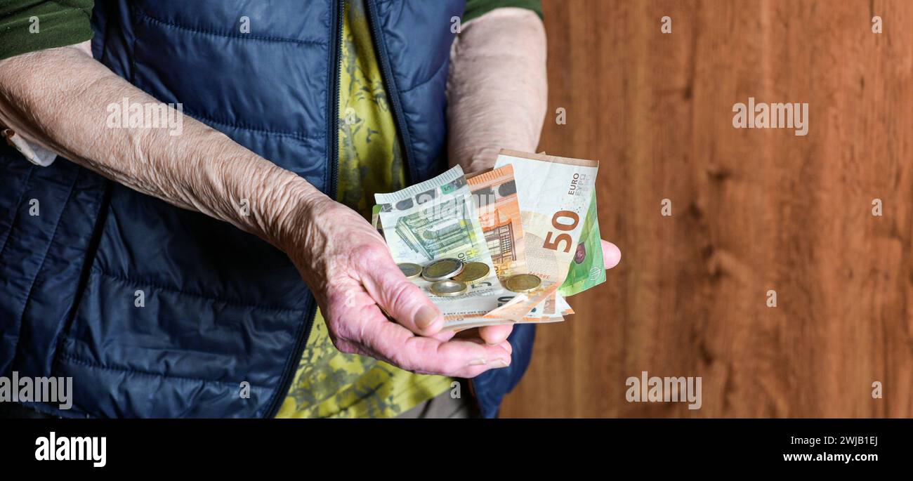 Rentner hält Geldwechsel und Papiergeld in der Hand, aus nächster Nähe - armer Rentner. Stockfoto