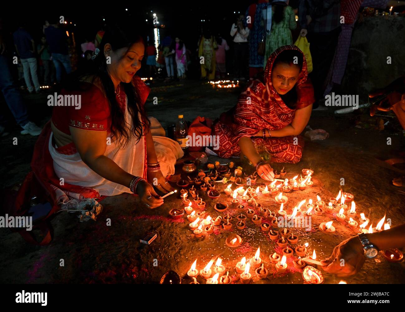 Indische Frauen, die Abendgebete mit einer schwimmenden Lehmlampe am Ufer des Ganges in Kalkutta, Indien, durchführen. Stockfoto