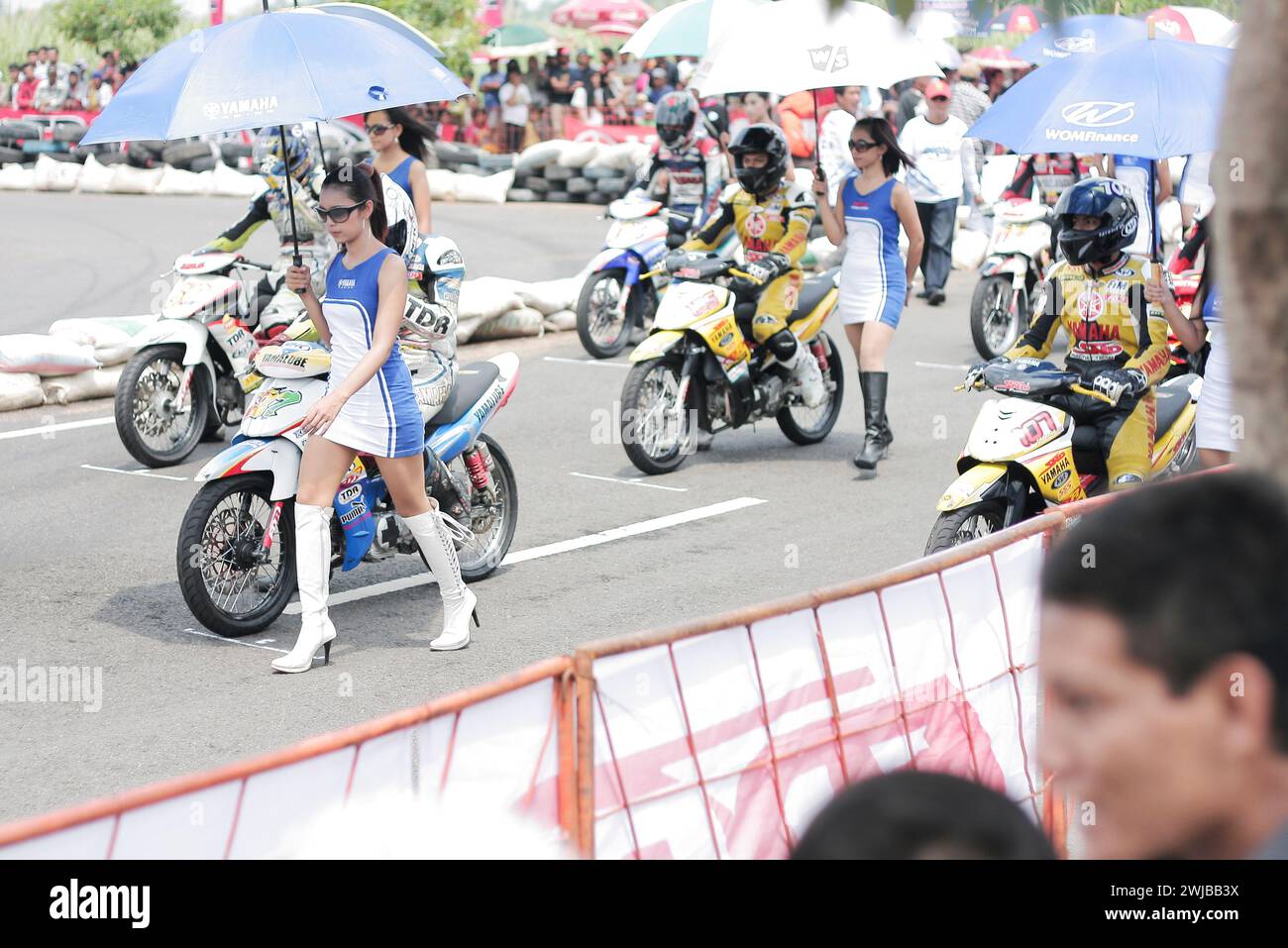 Underbone Motorradrennfahrer mit asiatischen Regenschirmmädchen auf der Start-Line Motorsport-Rennstrecke in Kediri, Ost-Java, Indonesien Stockfoto