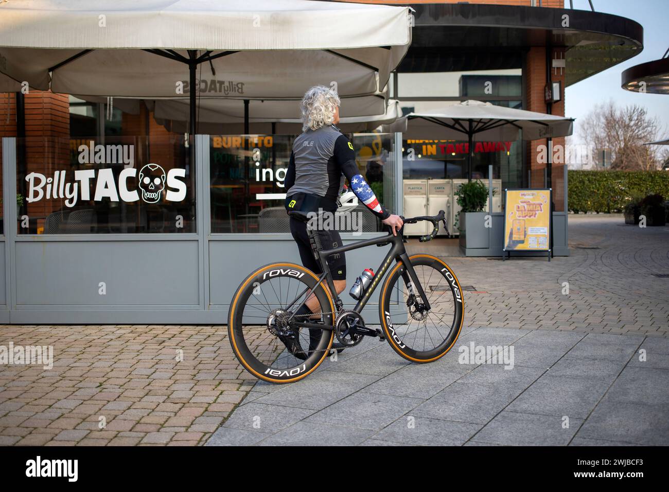 Novara, Italien, 16. Januar 2024: Ein Radfahrer, der ein Fahrrad schiebt, verlässt das Einkaufszentrum „Vicolungo the Style Outlets“ Stockfoto