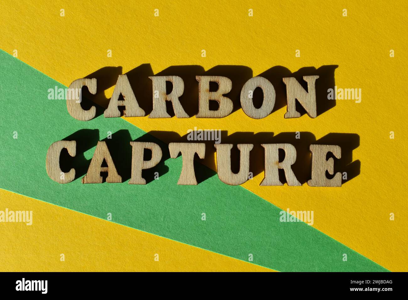 Carbon Capture, Wörter in Holzbuchstaben isoliert auf gelbem und grünem Hintergrund als Bannerüberschrift Stockfoto