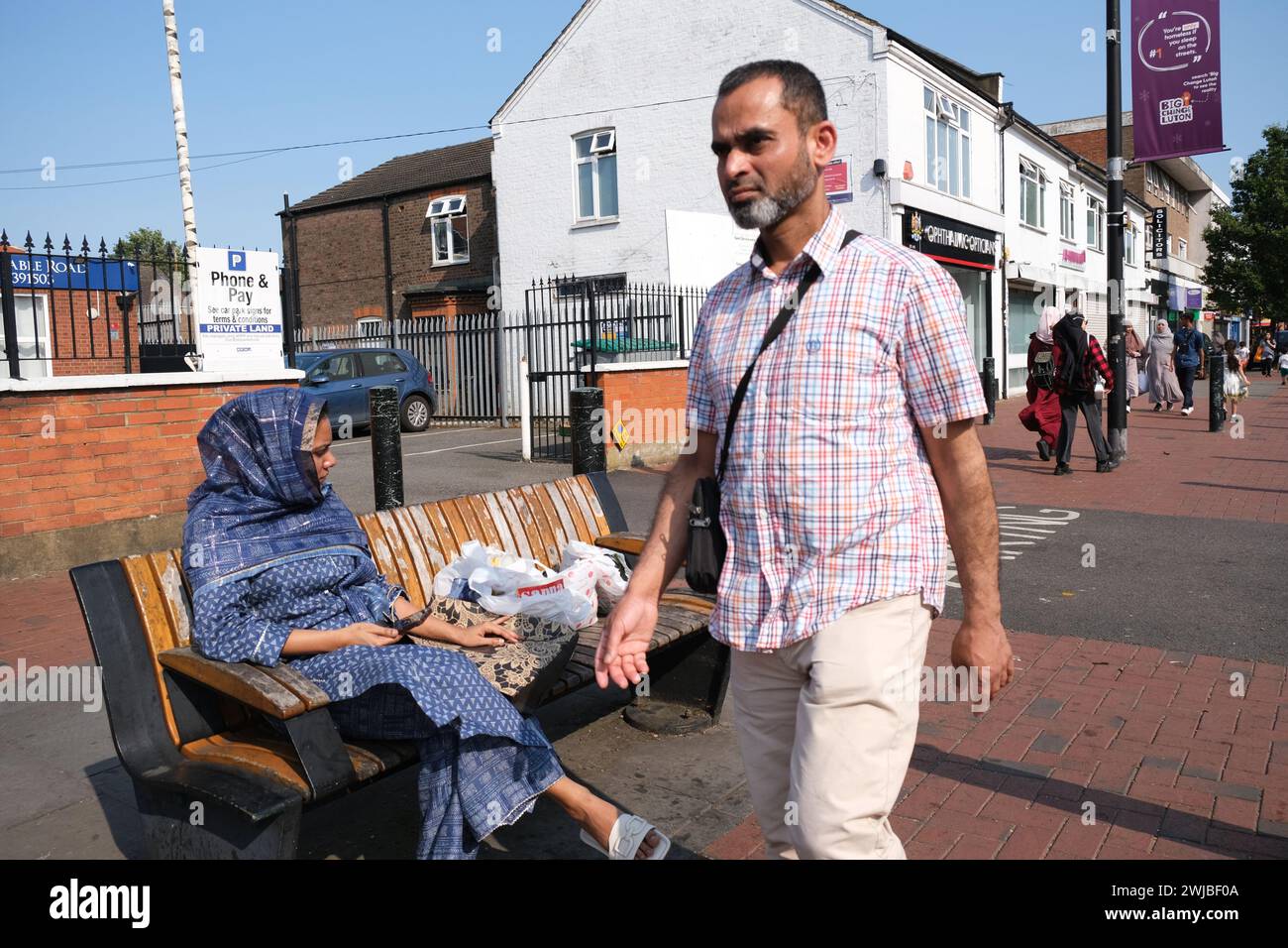 Asiatischer Mann geht an asiatischer Frau im Bury Park vorbei, einem multikulturellen Teil von Luton im Südosten Großbritanniens Stockfoto