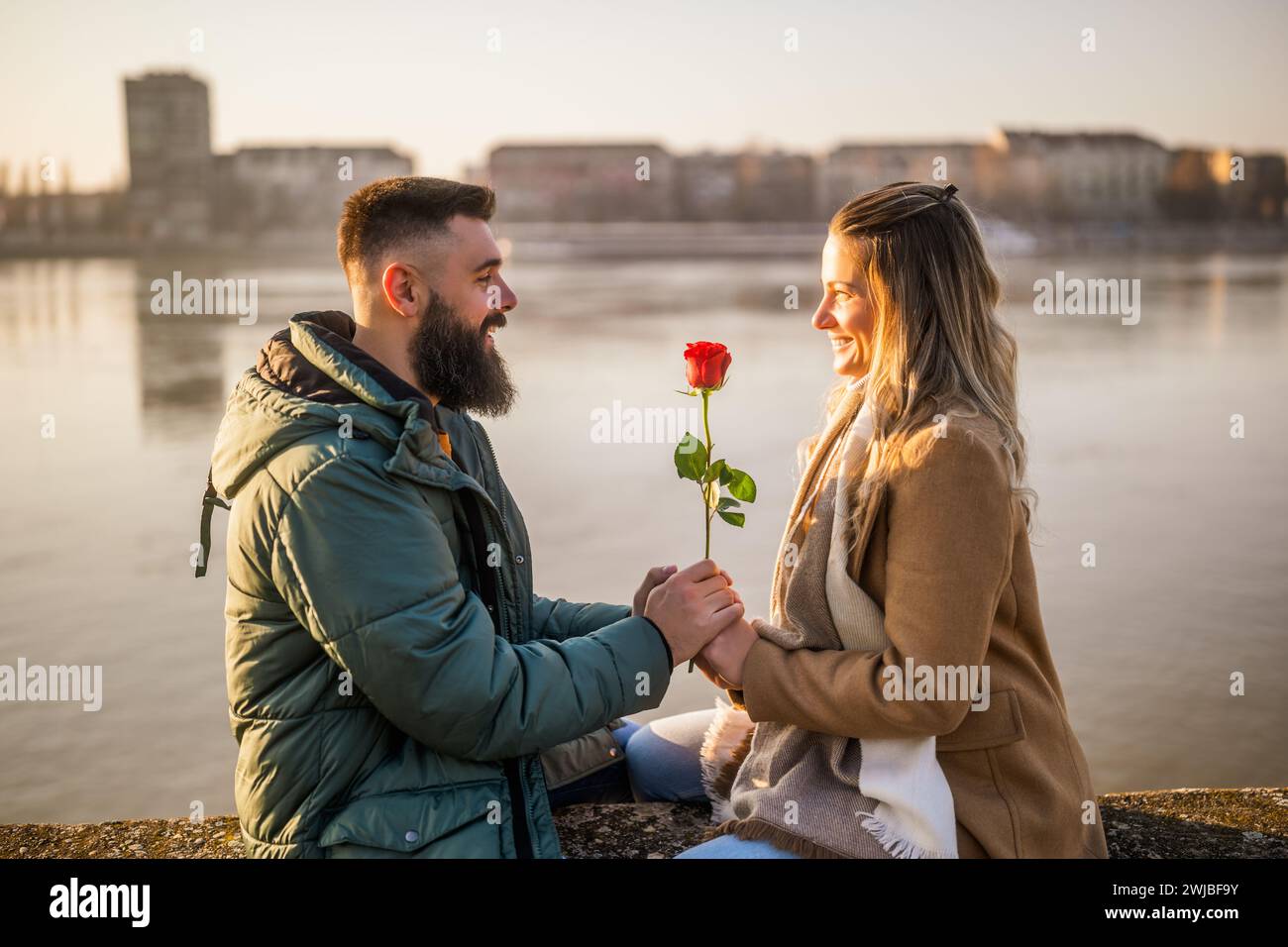 Ein Mann gibt seiner Frau rote Rose, während sie gern Zeit im Freien verbringen. Stockfoto